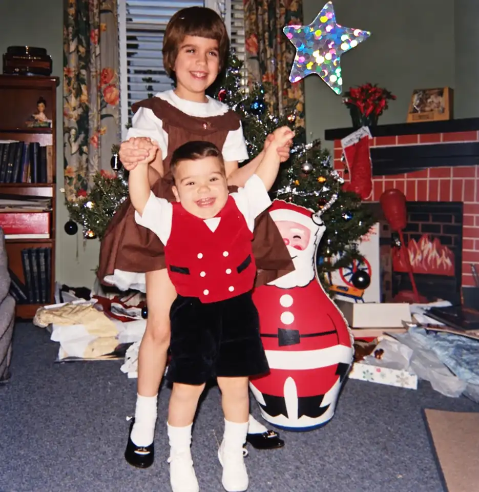 Two children celebrating Christmas beside a decorated tree