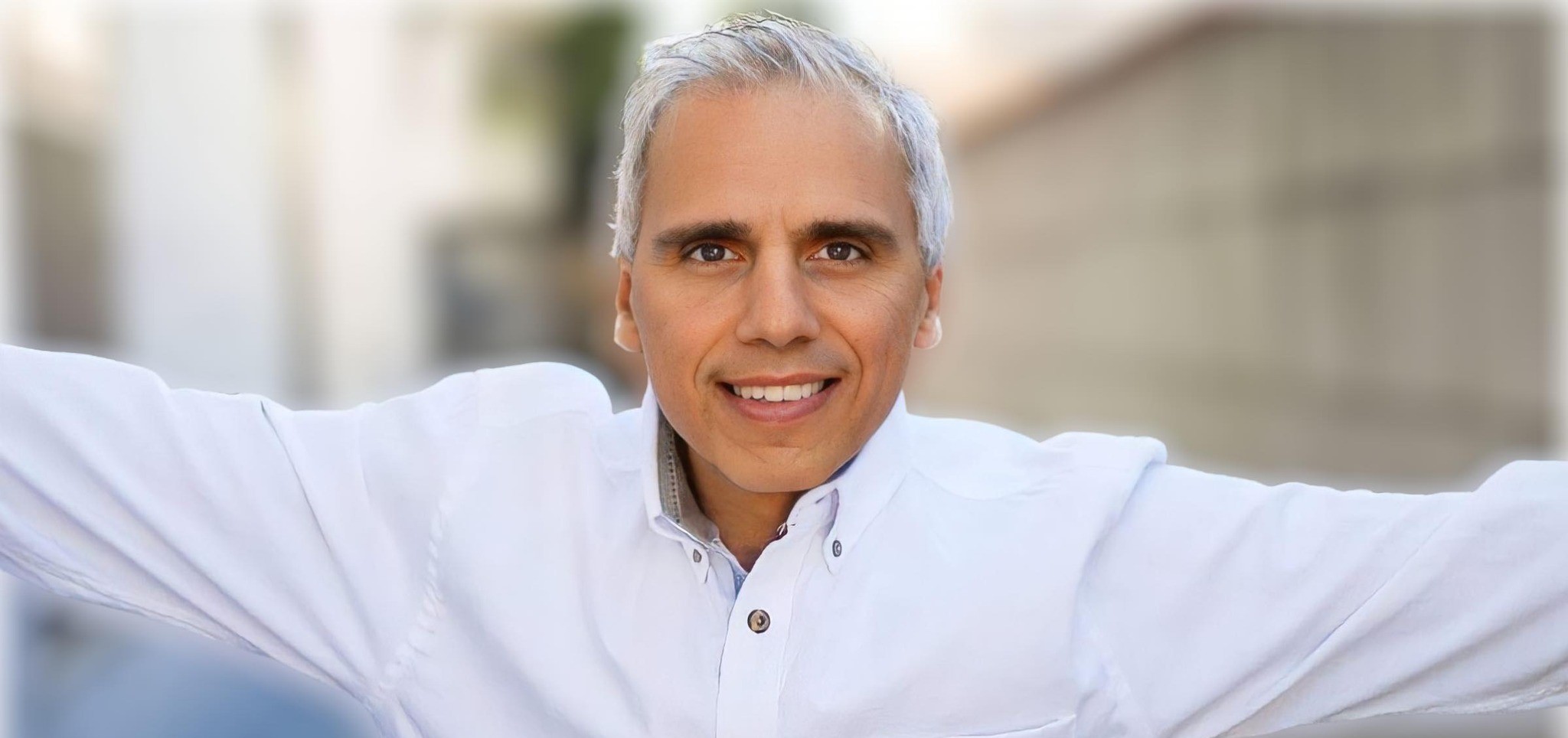 Herbie J Pilato smiling with his arms open in a white jacket