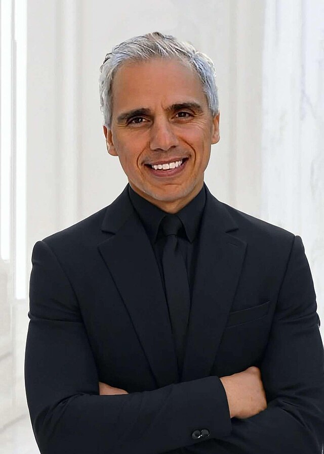 Herbie J Pilato smiling in a black suit and tie